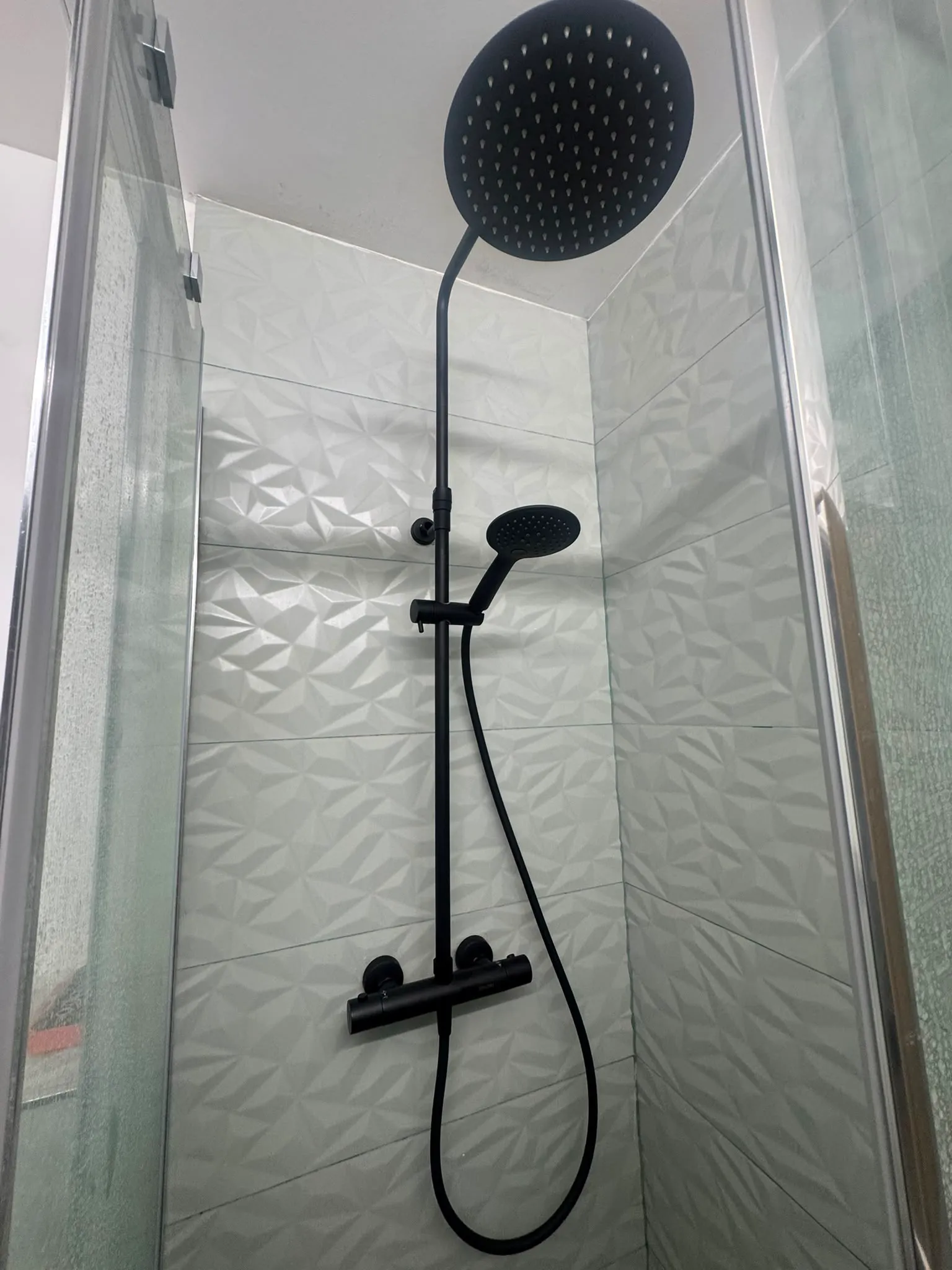 Colonne de douche installée proprement dans une salle de bain carrelée