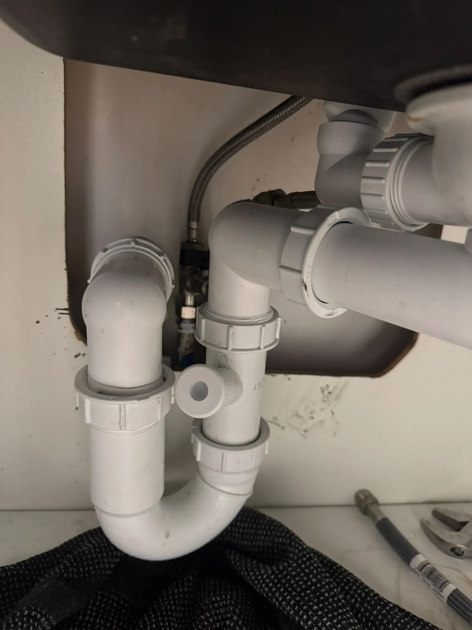 Intervention sous un évier : nettoyage du siphon avec les outils du plombier