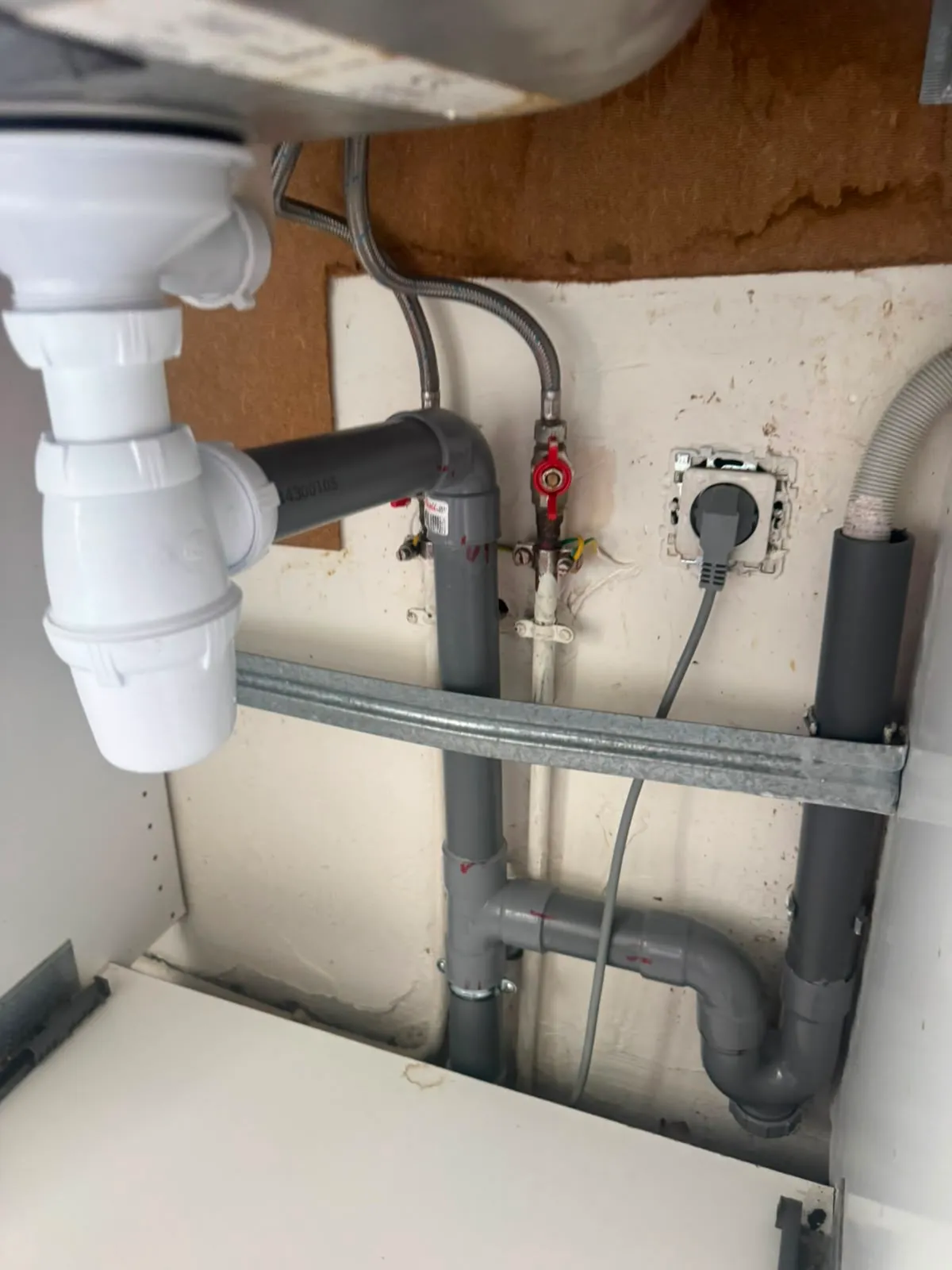 Nettoyage du siphon sous l'évier avec les outils du plombier